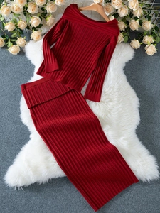 Flat lay of red off-shoulder ribbed knit sweater and matching skirt on white fur rug