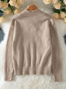 Gros plan d'un pull en maille beige avec poignets côtelés et texture douce en mohair