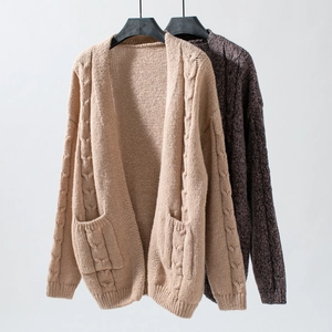 Macro detail of chunky cable knit texture and large front pockets on a long sleeve cardigan