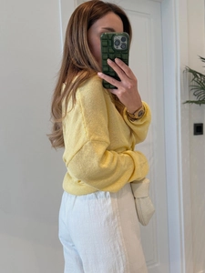 Dettaglio di un maglione in maglia giallo chiaro con polsini a coste e girocollo