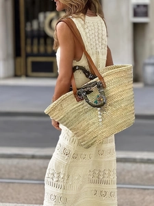 Elegant woven tote bag with leather straps and decorative silk scarf on a white dress