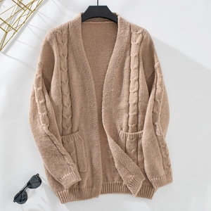 Close-up of cable knit cardigan sweater featuring ribbed cuffs and two front pockets