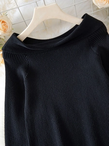 Detail of black ribbed knit texture on an elegant off-shoulder long sleeve sweater