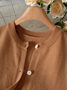 Close-up of caramel brown knitted cardigan showing ribbed crew neck and white buttons