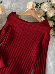 Detail of burgundy ribbed knit sweater showing elegant off-shoulder neckline on a hanger