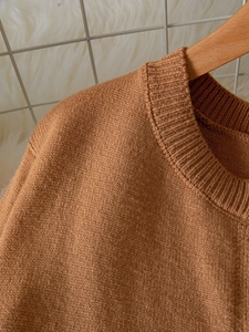 Close-up of brown knit sweater featuring ribbed crew neck and fine wool blend texture