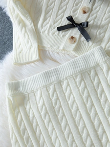 Vue détaillée du tricot torsadé et du nœud noir sur un cardigan en maille crème doux