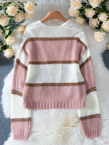 Close-up of elegant color-block knit sweater with lantern sleeves on fur background