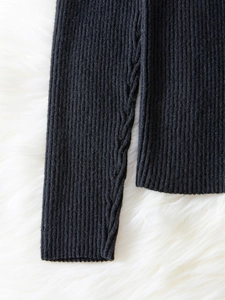 Detail of black off-shoulder knit sweater with ribbed texture and cable-knit hem