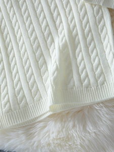 Détail de la maille torsadée blanche et de l'ourlet côtelé sur cet ensemble tricoté