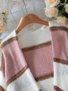 Close-up of pink and white striped knit cardigan texture on a wooden hanger