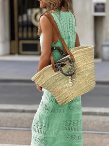 Detail of bohemian straw tote bag with silk scarf handle and pearl charm on lace dress