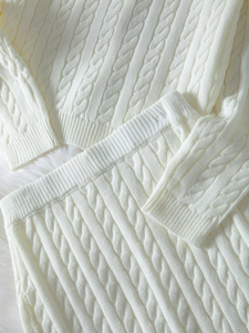 Gros plan sur la maille torsadée et les poignets côtelés d'un ensemble en tricot blanc