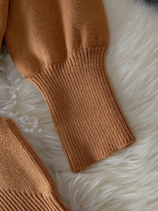 Close-up of fine knit texture and long ribbed cuffs on an elegant camel cardigan sweater