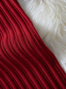 Detailed macro view of the red ribbed knit fabric texture on a white plush background
