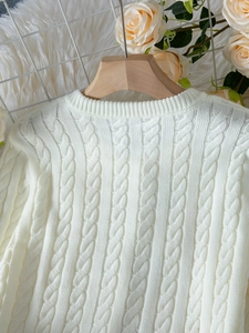 Détail de la texture en maille torsadée blanche et du tissu doux de l'ensemble tricot