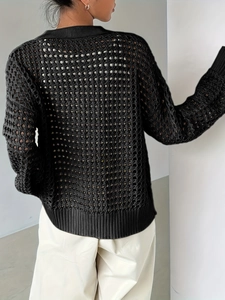 Dettaglio della trama del cardigan nero lavorato a maglia con design a rete traforata