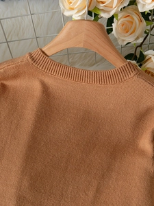 Detail of round ribbed neckline and fine knit texture on an elegant warm brown sweater