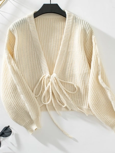 Close-up of cream knit cardigan featuring ribbed texture and front tie-up drawstring detail