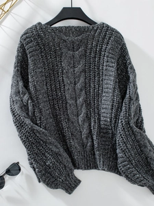 Detail der dunkelgrauen Zopfstrickstruktur und der dicken Strickmuster am Winterpullover