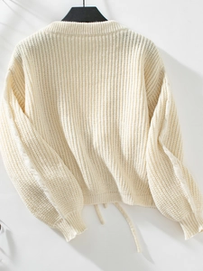 Close-up of white knit sweater showing textured ribbing and soft chunky knit fabric