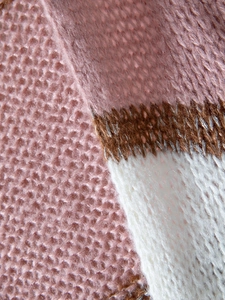 Macro detail of soft chunky knit fabric showing pink, brown and white textured patterns