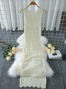 Close-up of the intricate hollow-out knit pattern and scalloped hem on the beige dress