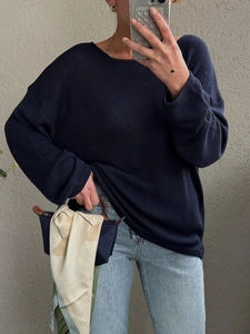 Dettagli del maglione in maglia blu scuro con scollo tondo e foulard di seta sulla borsa