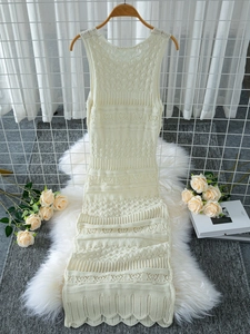 Detail of cream sleeveless crochet dress with scalloped hem and hollow knit patterns