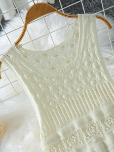 Close-up of cream hollow-out knit dress showing intricate crochet details and texture