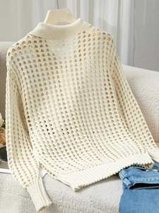 Dettaglio di un elegante cardigan beige in maglia traforata con bottoni in legno classici