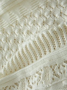 Macro detail of creamy white knit dress showing hollow-out geometric patterns and ribbing