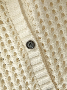 Dettaglio cardigan in maglia traforata color crema con bottoni grigi e bordi a coste
