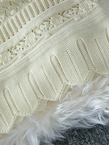 Detail of hollow knit pattern and scalloped edge on an elegant beige sleeveless dress