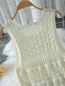 Detail of cream white sleeveless knitted dress with geometric openwork and scallop edges