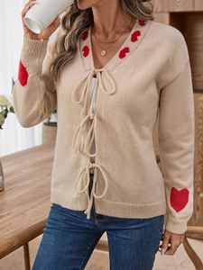 Elegant beige knit cardigan with red heart patterns and stylish front bow-tie closure