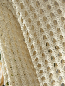 Dettaglio ravvicinato del tessuto beige a maglia traforata con trama a nido d'ape