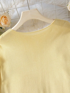 Dettaglio dello scollo del maglione in maglia giallo chiaro su gruccia con decori floreali