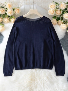 Dettaglio di maglione in maglia blu scuro con polsini a coste su tappeto di peluche