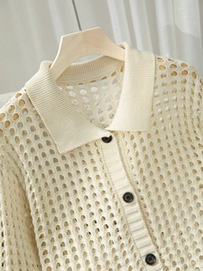 Dettaglio del cardigan polo in maglia traforata con bottoni marrone scuro su gruccia