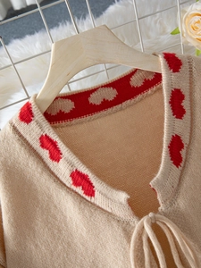 Detail of V-neck knit cardigan with contrast heart pattern trim and front tie fastening