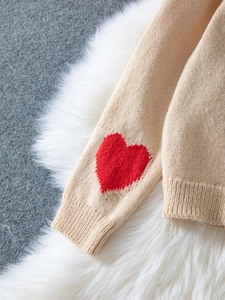 Detail of knit cardigan sleeve with red heart pattern on beige soft fabric