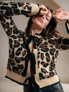 Détail du cardigan léopard avec nœuds en ruban noir et texture en maille douce et moelleuse