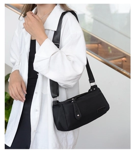 Close-up of black nylon shoulder bag with adjustable wide strap and silver metal buckle