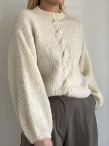 Women's cream cable knit sweater with a round neck and loose fit paired with trousers
