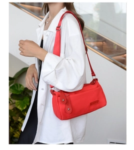 Detail of red nylon crossbody bag featuring stylish leather tassels and brand logo patch