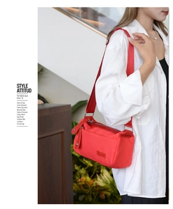 Red nylon crossbody bag with wide strap and silver zipper shown on a model