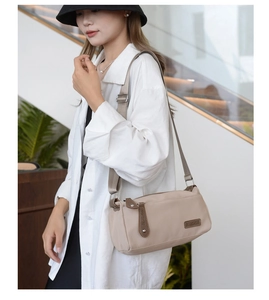 Minimalist beige nylon crossbody bag shown from a top-down view on a model