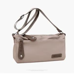 Detail of khaki nylon crossbody bag showing the adjustable strap and leather pullers