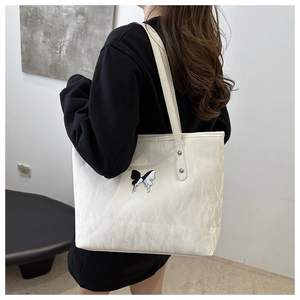 White tote bag with marble texture and butterfly patch detail shown on shoulder